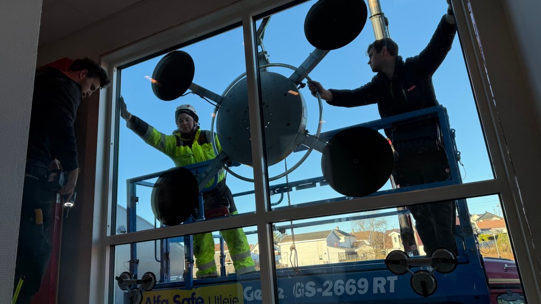 Tømrerne Bjørn Nerås og Thomas Bekkeheien fra Byggelaget. Nerås manøvrerer vindusoperasjonen fra innsiden, mens Bekkeheien styrer i liften på utsiden.